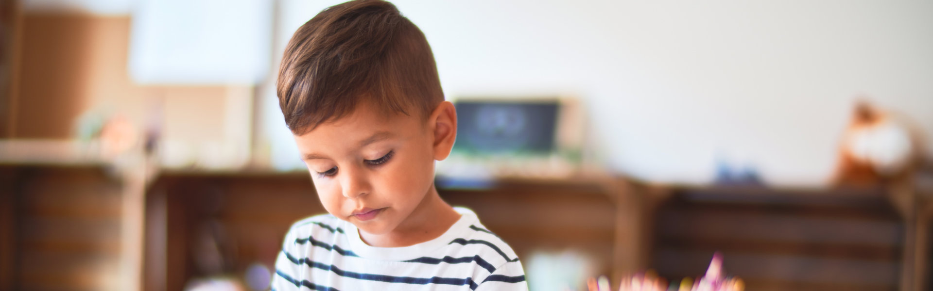 Beautiful toddler boy drawing cute draw using colored pencils at kindergarten