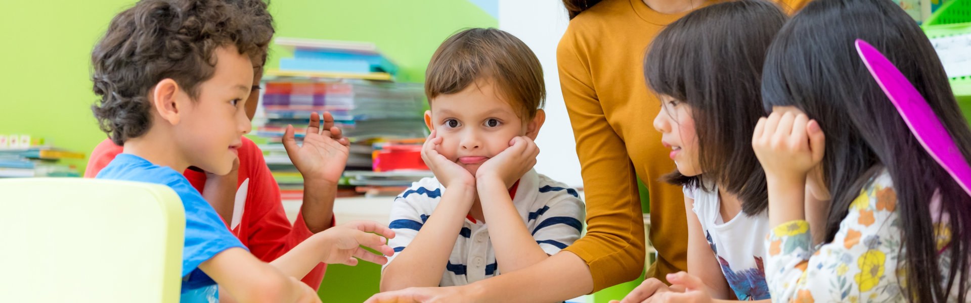 female teacher teaching mixed race kids reading book in classroom,Kindergarten pre school concept