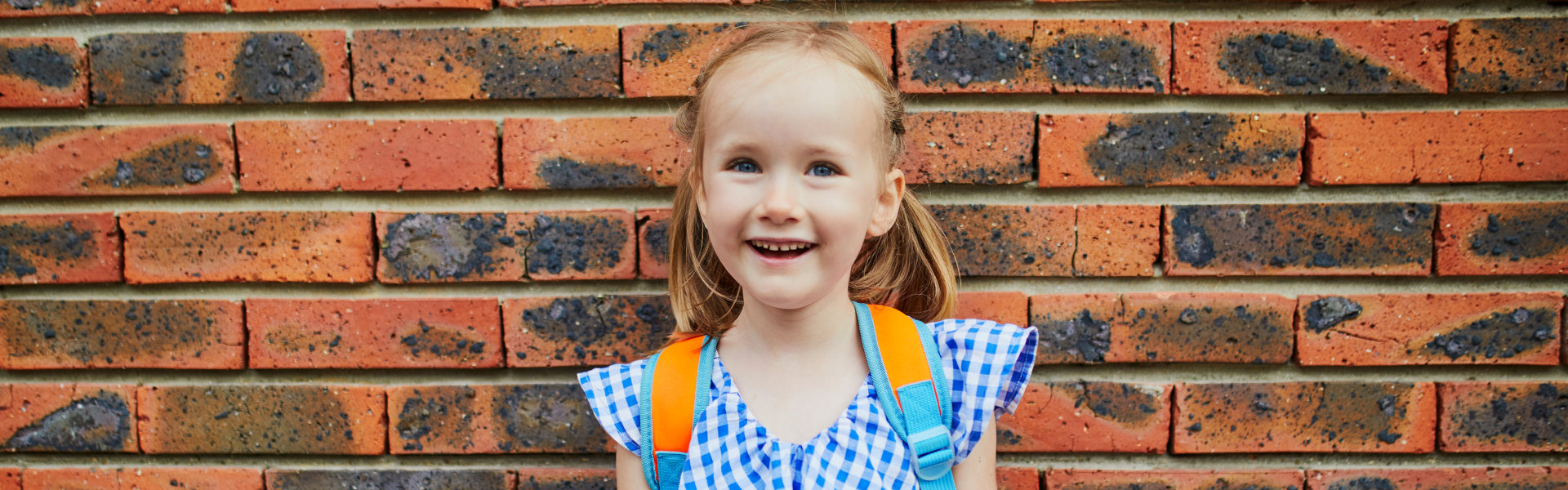 Cheerful 4 years old girl holding a poster with text `My first day in kindergarten` written in French